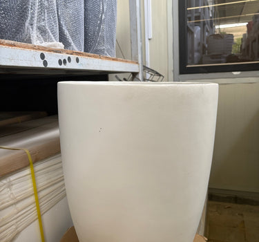 White Arco Fiber Pot with Matte Finish and Lifetime Warranty, UAE. White cylindrical object on a construction site with tools and materials in the background